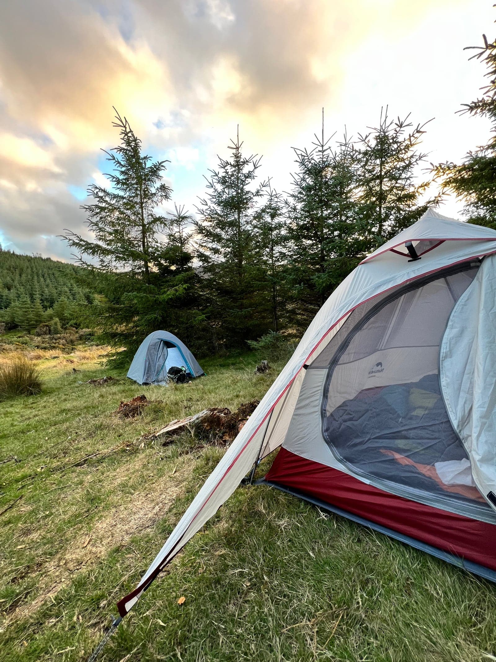 Two tents on a hilly and grassy terrain