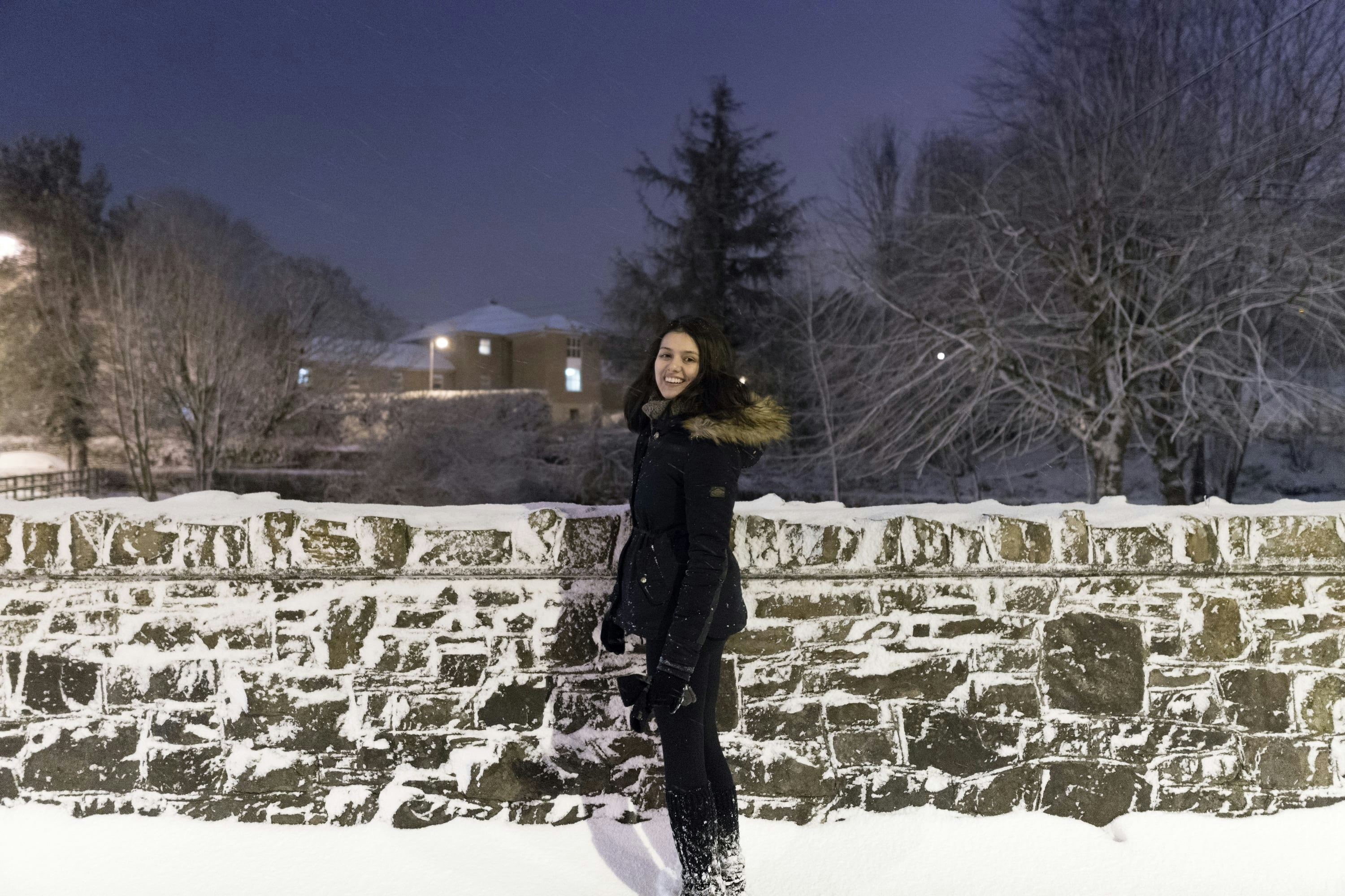 Laura in front of stone wall covered in snow
