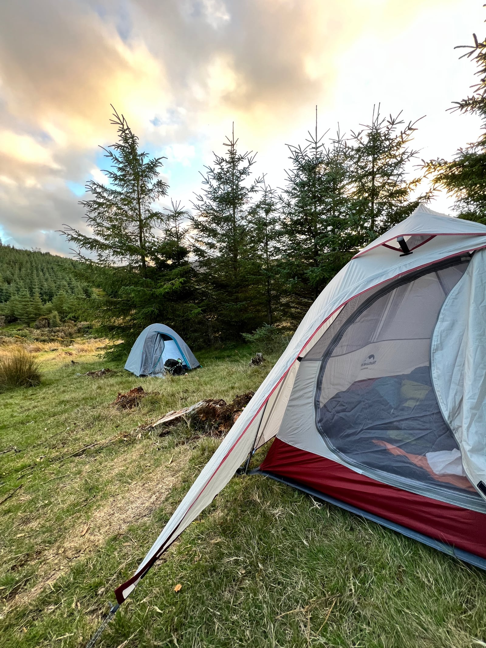 Two tents on a hilly and grassy terrain